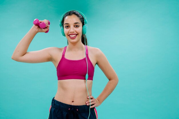 Young woman with earphones and dumbbell