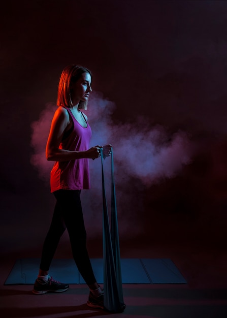 Free photo young woman with elastic rope in dark