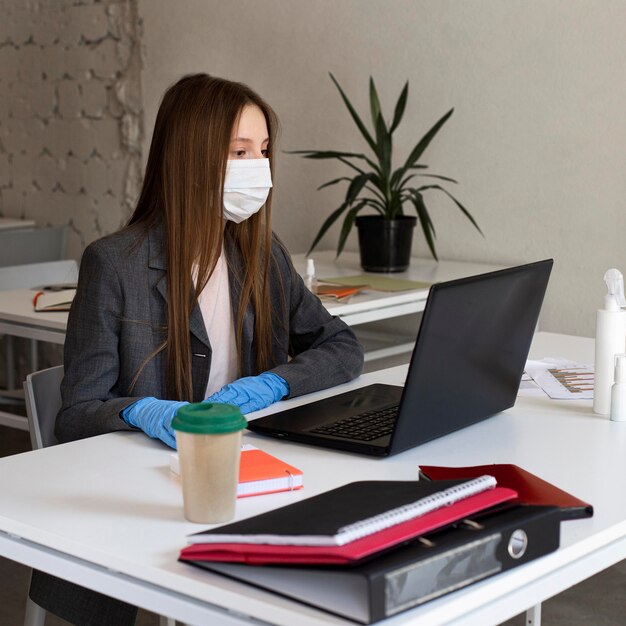 Young woman with face mask working at the office