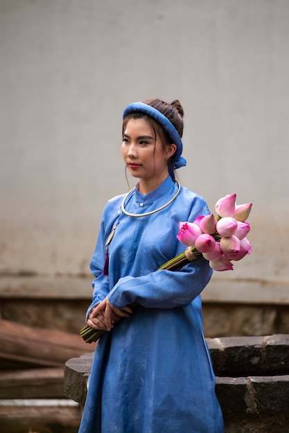 Free Photo young woman with flower bouquet wearing ao dai costume