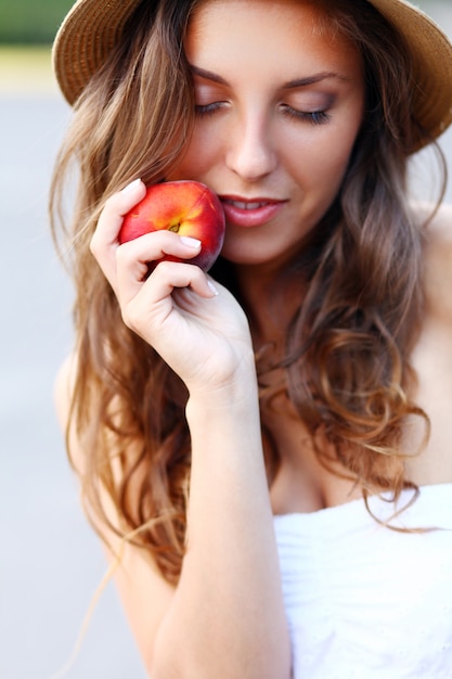 Young woman with fresh peach in her hand