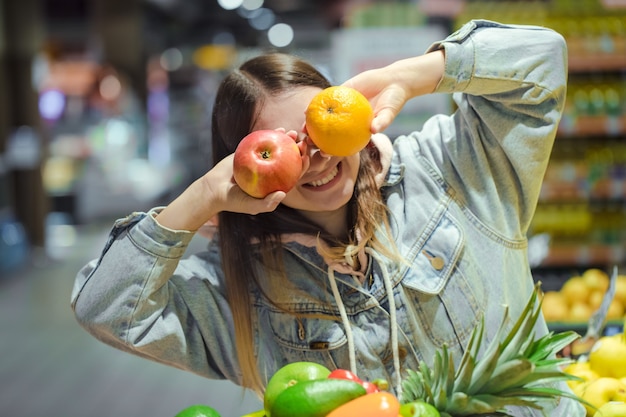 Free photo young woman with fruit in her hands in the supermarket .