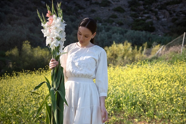 Young woman with gladiolus in nature