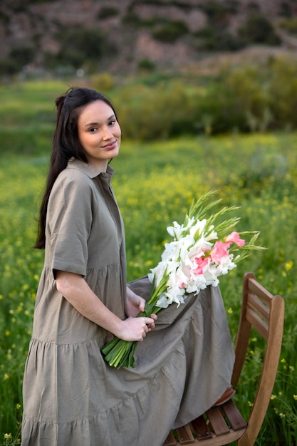 Young woman with gladiolus in nature