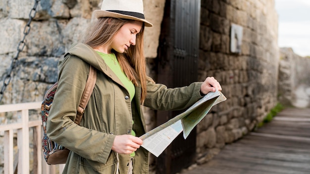 Free photo young woman with hat checking map