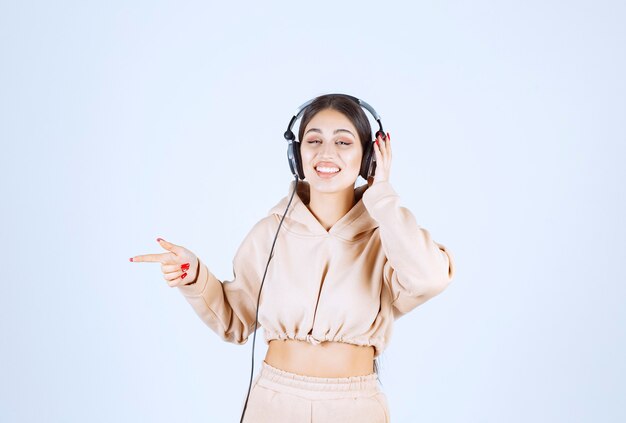 Young woman with headphones pointing or noticing someone on the left