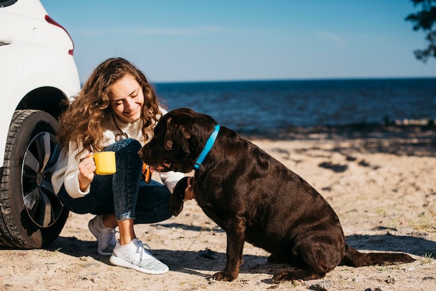 Free photo young woman with her dog at the beach