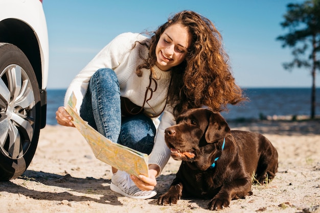 Free photo young woman with her dog at the beach