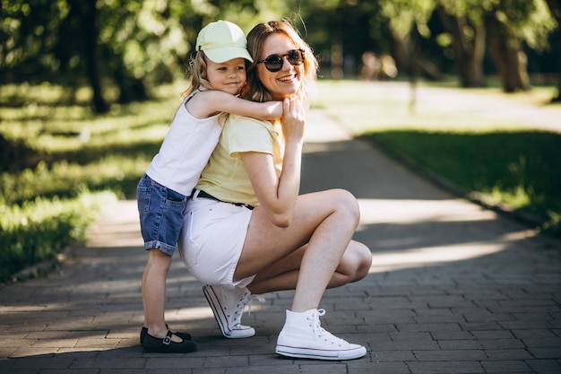 Young woman with little daughter walking in park