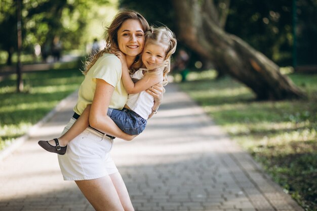 Young woman with little daughter walking in park