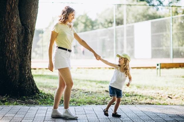 Young woman with little daughter walking in park