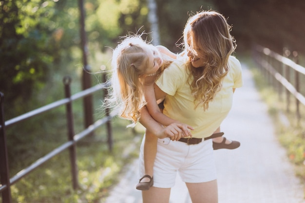 Young woman with little daughter walking in park