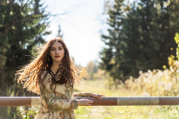 Young woman with long red hair in a linen dress gathering mushrooms in the forest 