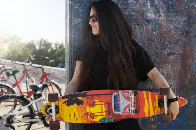 Young woman with longboard near wall