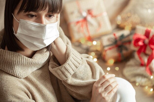 Young woman with mask on her face in a cozy beige sweater