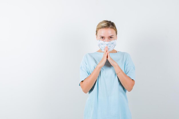 Young woman with a medical mask praying