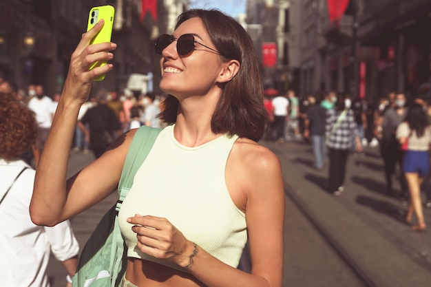 Young woman with mobile phone travels through the crowded streets of istanbul happy enjoying the beauty of the city