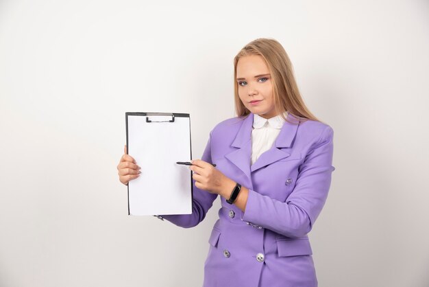 Young woman with pencil holding tablet on white.