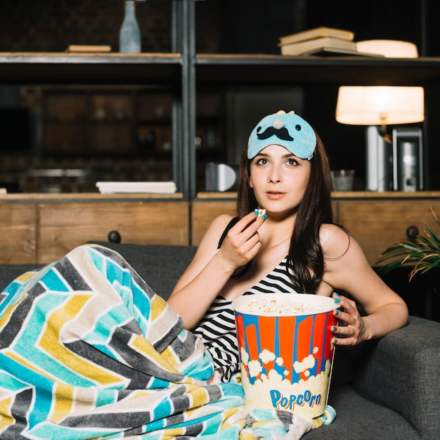 Young woman with popcorn watching television