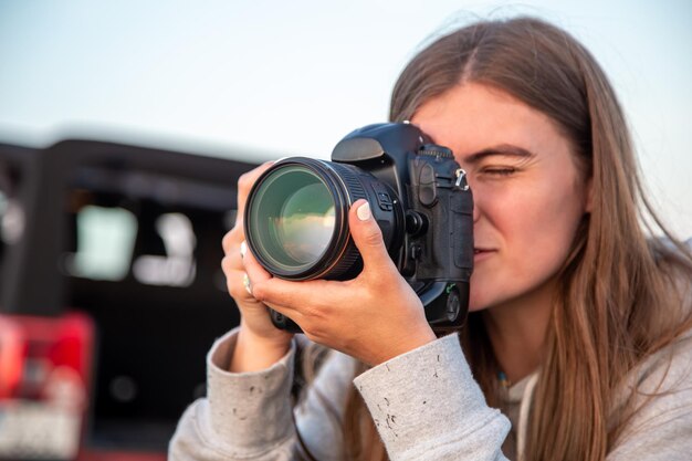 A young woman with a professional camera takes a photo in nature