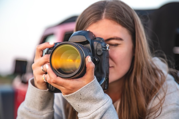 A young woman with a professional camera takes a photo in nature