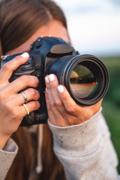 A young woman with a professional camera takes a photo in nature