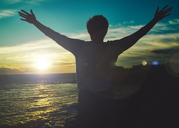 Free Photo young woman with raised hands greeting sun