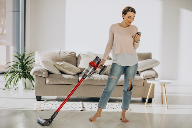 Young woman with rechargeable vacuum cleaner cleaning at home