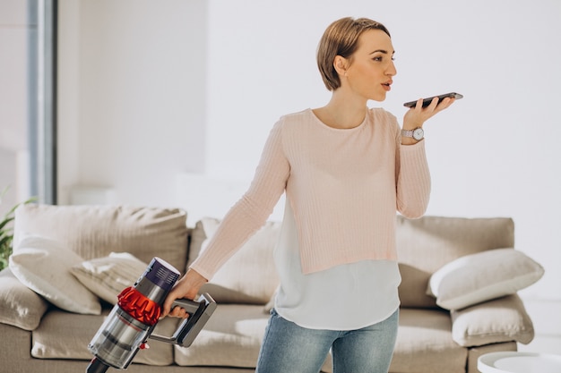 Free photo young woman with rechargeable vacuum cleaner cleaning at home