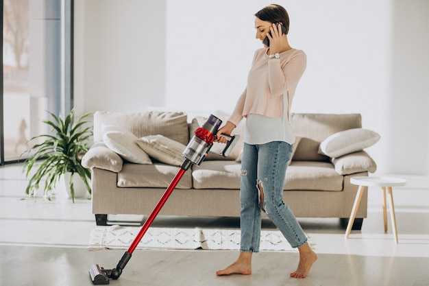 Young woman with rechargeable vacuum cleaner cleaning at home