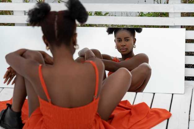 Young woman with red dress posing outside in mirror