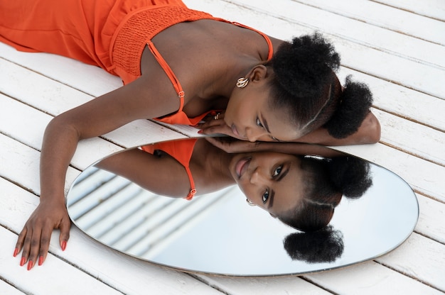 Young woman with red dress posing outside in mirror