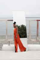 Free photo young woman with red dress posing outside in mirror