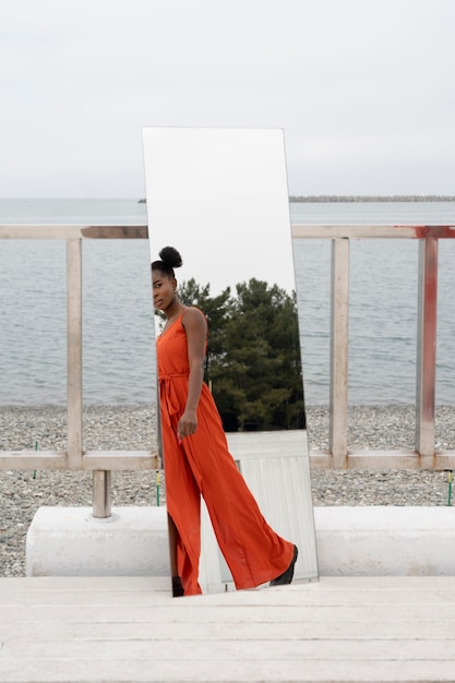 Young woman with red dress posing outside in mirror