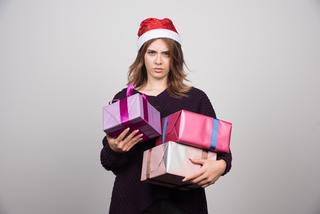 Free photo young woman with santa hat holding gift boxes presents.