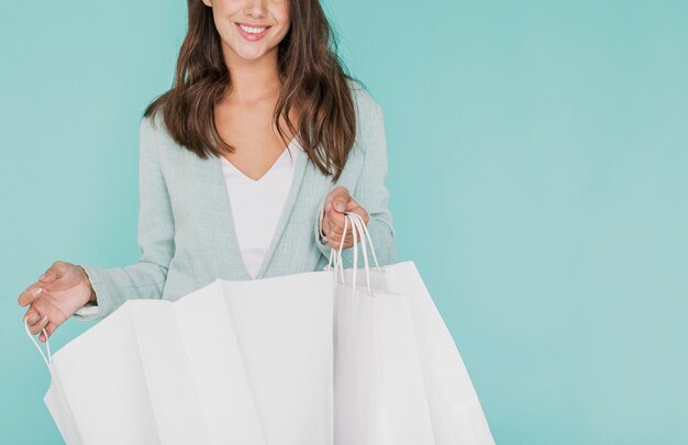 Young woman with shopping bags on blue background