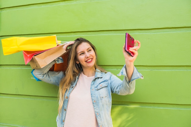 Free Photo young woman with shopping bags taking selfie 