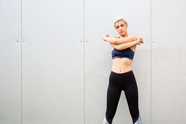 Young woman with short hair stretching outdoors