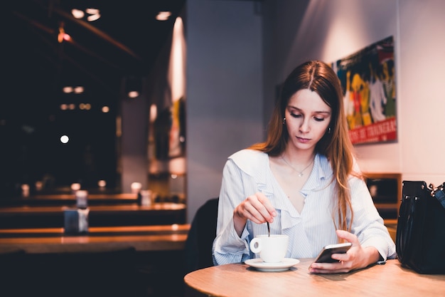 Free photo young woman with smartphone mixing beverage