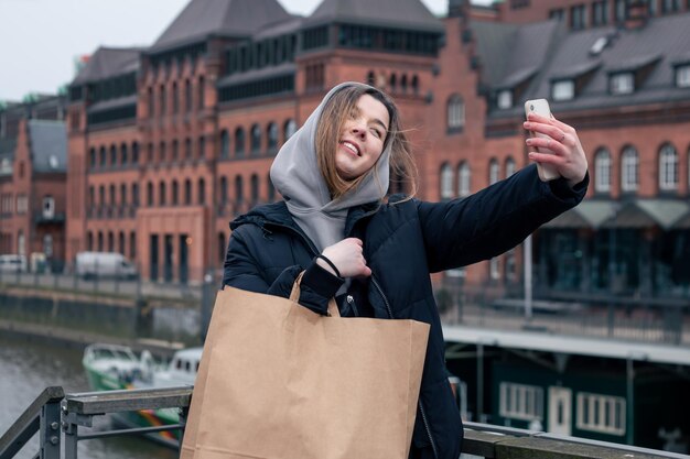 A young woman with smartphone and shopping bag in the city