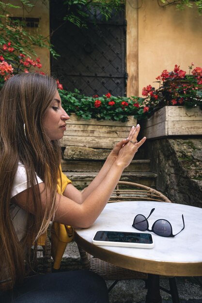 A young woman with smartphone and sunglasses in a cafe on the terrace