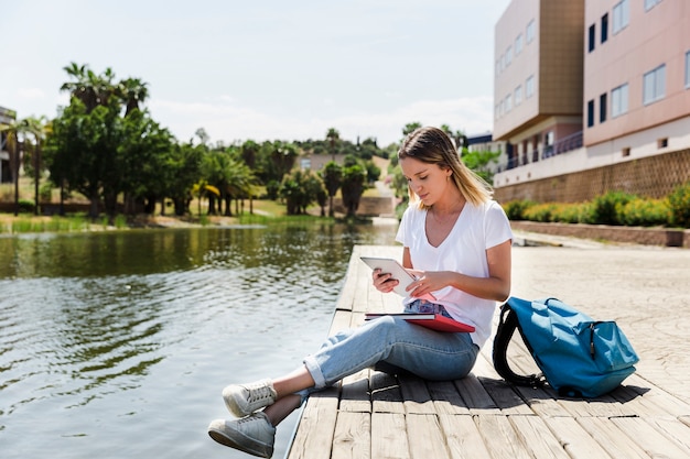 Free photo young woman with tablet in campus near lake