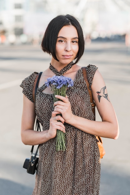 Free Photo young woman with tattoo holding flowers