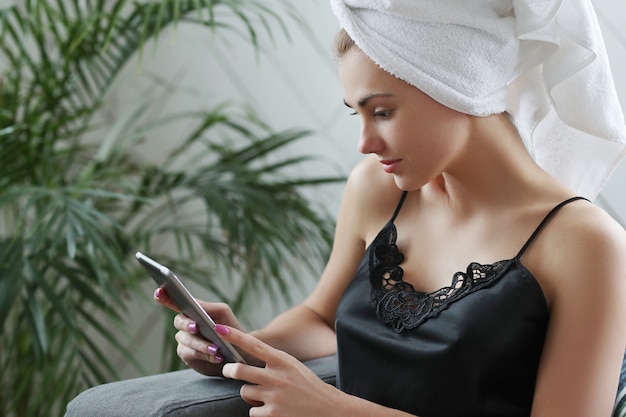 Free photo young woman with towel on her head, using digital tablet