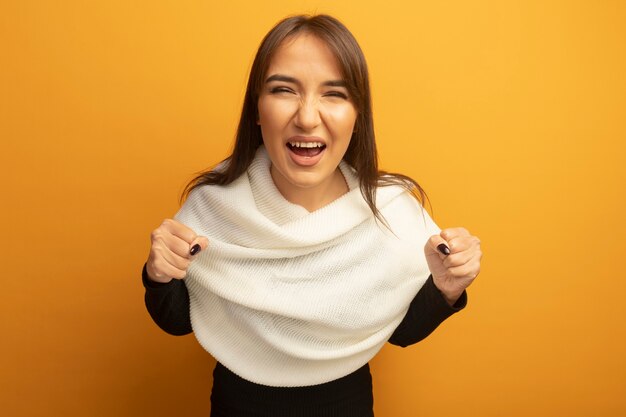 Young woman with white scarf clenching fists happy and excited 