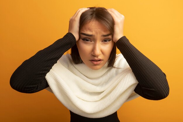 Young woman with white scarf confused with hands on her head for mistake 