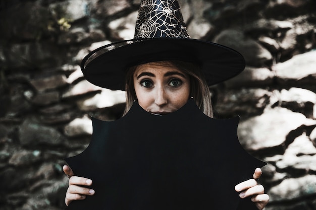 Young woman in wizard hat holding Halloween decoration