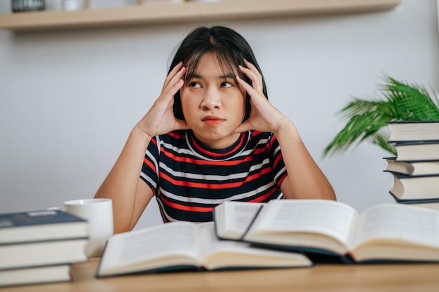 Young woman working on a book on the table and having stress