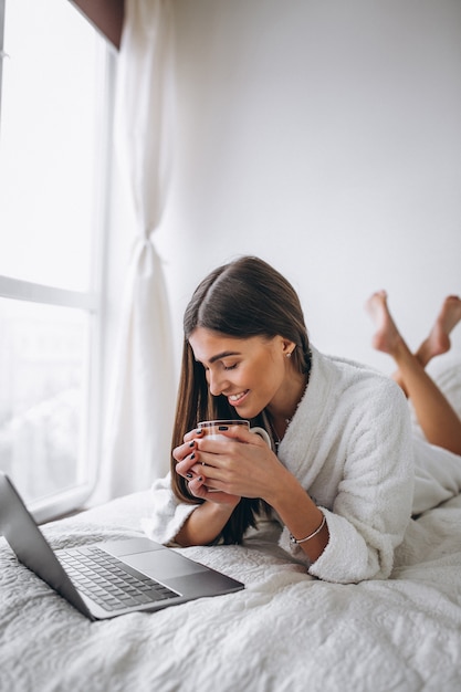 Young woman working on computer in bed