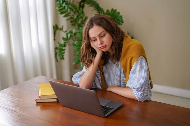 Free photo young woman working at freelance home office feels tired after work